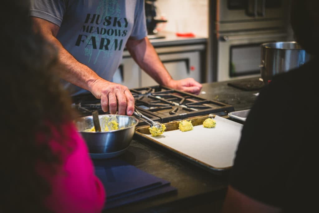 Person in Husky Meadows Farm shirt preparing food in kitchen